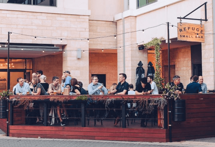 A group of people sit outside a small bar in the evening